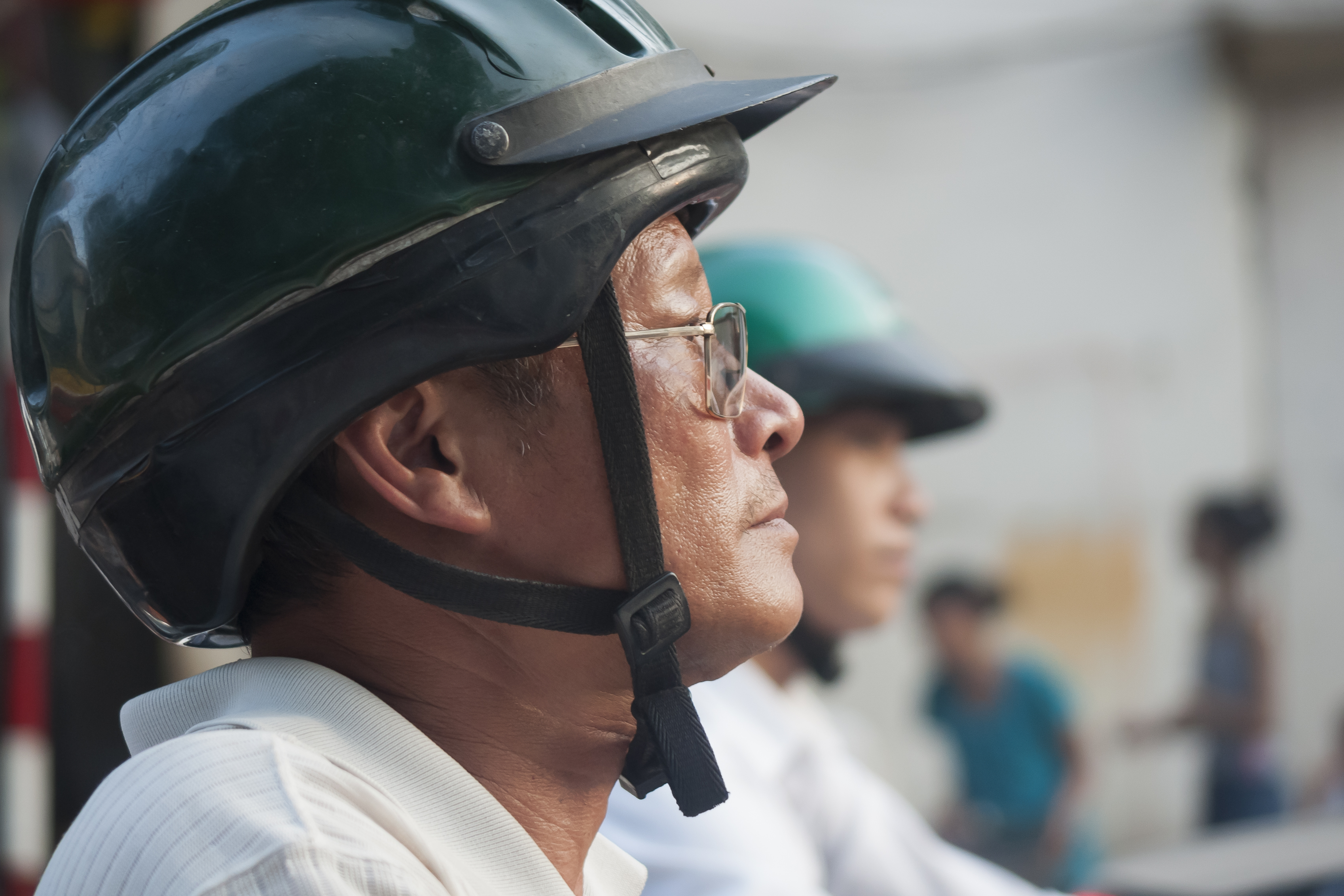 Người đi xe máy đội mũ bảo hiểm dừng chờ đèn đỏ trên phố Hà Nội
