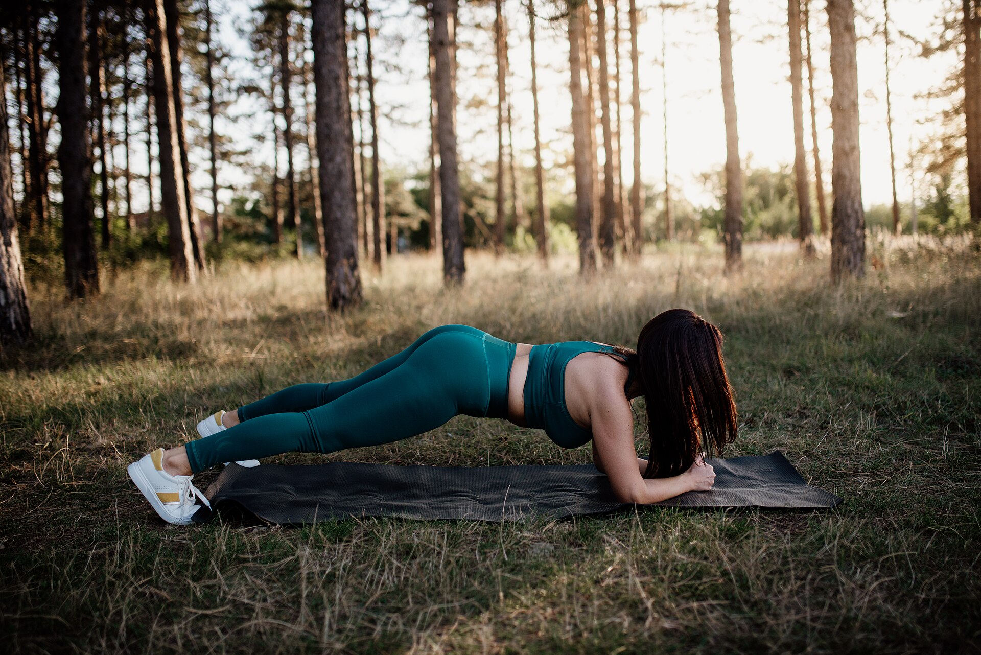Người phụ nữ tập plank trên thảm ngoài trời trong rừng buổi sáng