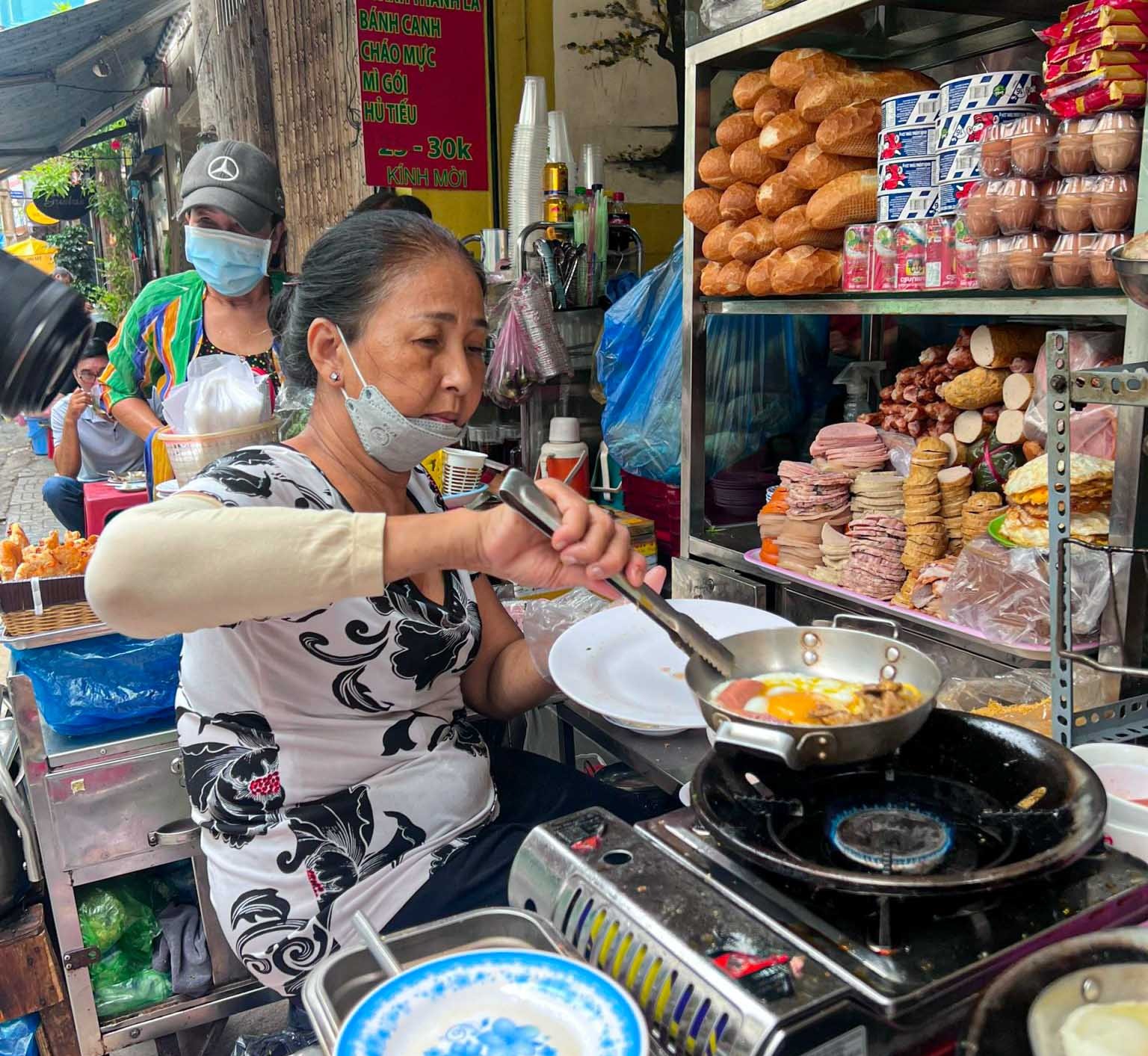 Người bán hàng chuẩn bị đồ ăn sáng tại một quầy nhỏ