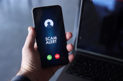 Bàn tay cầm điện thoại hiển thị cảnh báo cuộc gọi lừa đảo