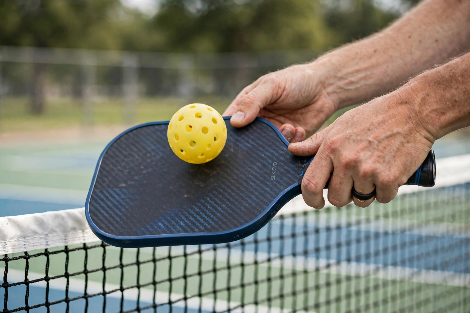 Ảnh minh họa: cận cảnh tay người cầm vợt pickleball thực hiện kỹ thuật dink gần lưới